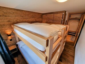 Uma cama beliche com cabeceira de madeira e uma pequena mesa de cabeceira com luminária.