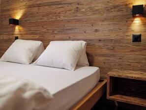 A bedroom with a wooden headboard, two white pillows, and a bedside table with a lamp. - Cornelia 1 Appartement/Fewo Appartement/Fewo by Interhome (Saas-Fee)