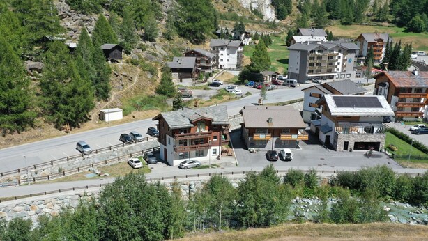 Un paisaje montañoso con estacionamiento, edificios y una carretera.