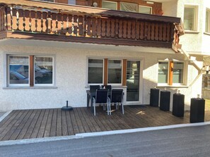 A building with a wooden deck, a table with chairs, and large windows. - Alpin Relax Appartement/Fewo Appartement/Fewo by Interhome (Saas-Almagell)