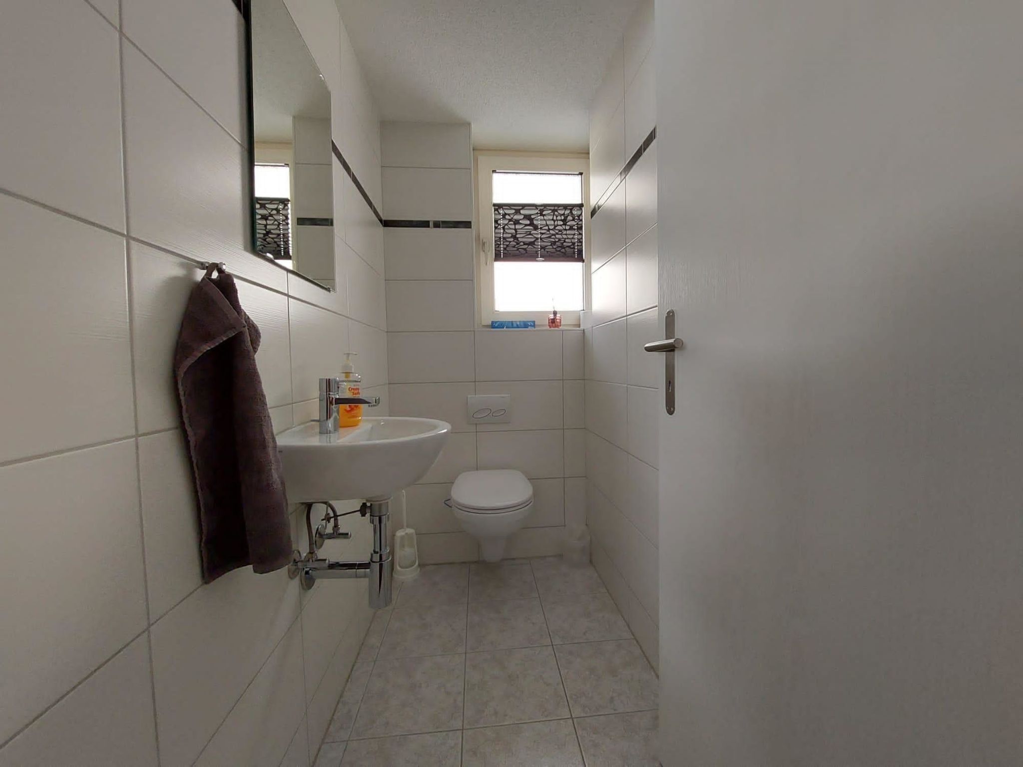 Een kleine badkamer met een wit wastafel, toilet en een handdoek aan de muur.