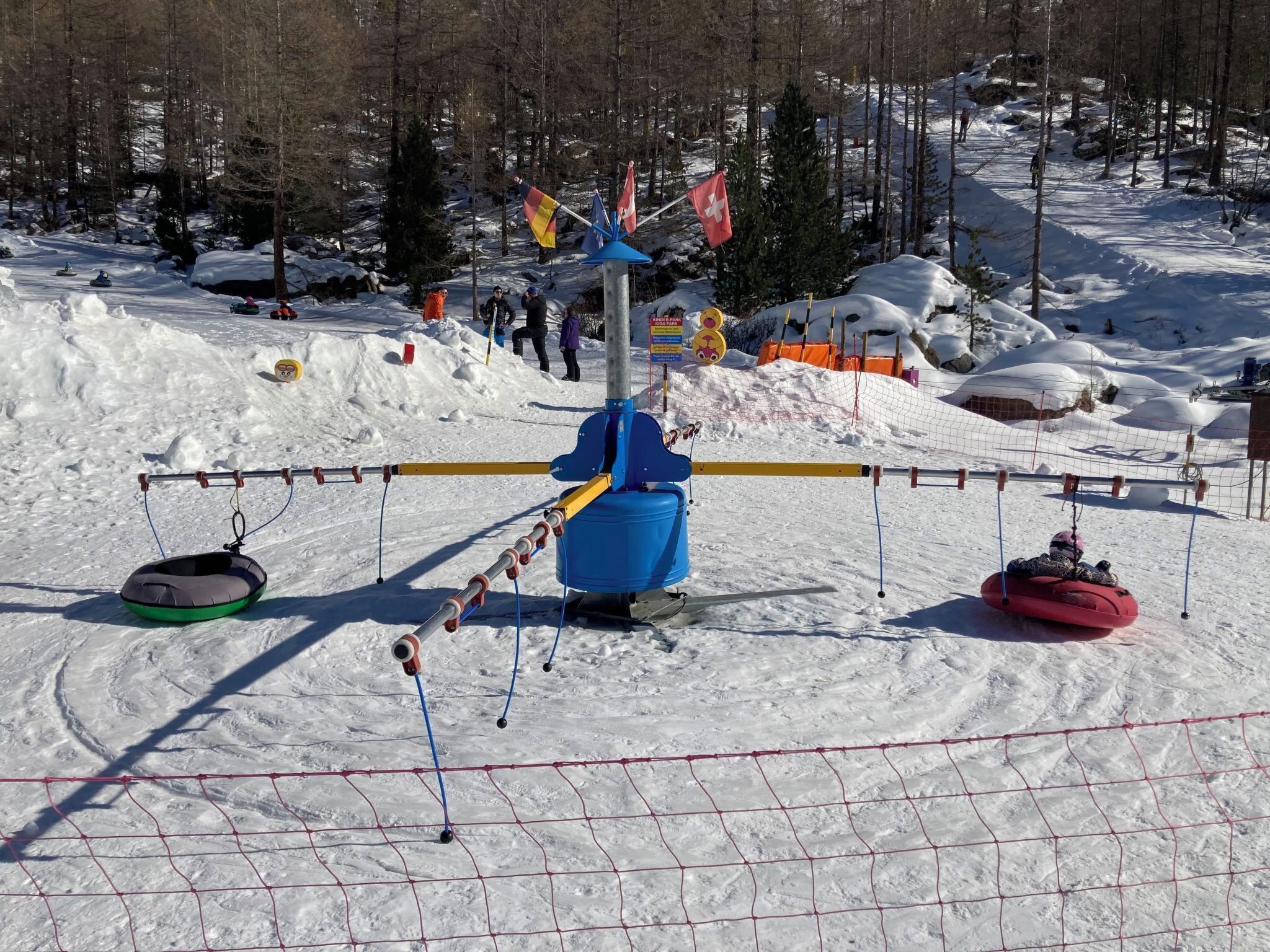 A snowy ski slope with a lift system, including a blue chairlift and two sleds.