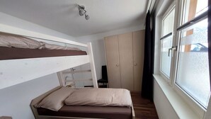 Dormitorio con literas, armario y ventana.