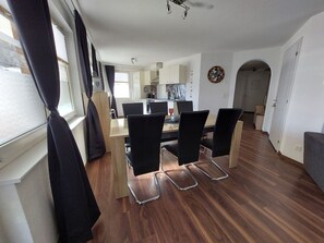 A modern dining area with a wooden table and black chairs, a kitchen in the background, and a hallway leading to another room. - Alpin Relax Appartement/Fewo Appartement/Fewo by Interhome (Saas-Almagell)