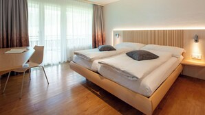 Ett modernt hotellrum med en stor säng, sängbord, ett skrivbord och en stol.
