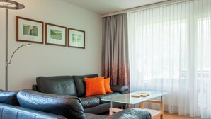 Ett modernt vardagsrum med en soffa i läder, ett soffbord i glas och en golvlampa.