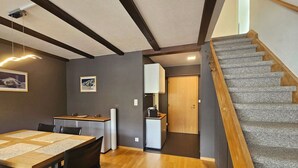 Une cuisine moderne avec un coin repas, un escalier et une porte donnant sur une autre pièce.