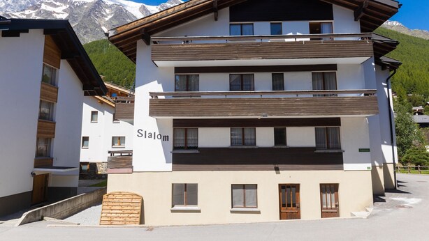 A multi-story hotel with a modern design, featuring balconies and a view of snow-capped mountains. - Haus Slalom Appartement/Fewo Apt #1 by Interhome (Saas-Fee)