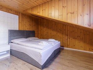 A bedroom with a bed, a nightstand, and wooden panel walls. - Haus Slalom Appartement/Fewo Apt #6 by Interhome (Saas-Fee)