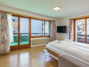 Ein Hotelzimmer mit Bett, Fernseher und Blick auf ein Gebäude durch das Fenster.