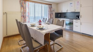 Una cocina compacta con comedor, que incluye una mesa preparada para cuatro personas, sillas y un radiador.