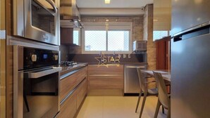 Una cocina moderna con electrodomésticos de acero inoxidable, armarios de madera y un amplio ventanal.