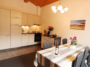 A modern kitchen with light-colored cabinets, a dining table set for two with a wine bottle, and a painting on the wall. - Azur Appartement/Fewo 4-Bettwohnung Nr. 10 by Interhome (Saas-Fee)
