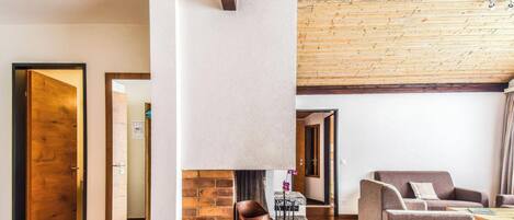 Un interior moderno con techo de madera, chimenea, sofá y mesa de centro.