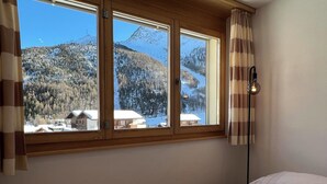 Ein Schlafzimmer mit großem Fenster, einem Bett und einer Stehlampe.