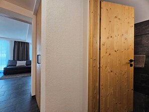 Ein modernes Interieur mit einer Holztür, einer strukturierten Wand und einem dunklen Boden.