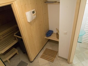Ein Zimmer mit Holzboden, einer Bank, einem kleinen Regal und einer wandmontierten Vorrichtung.