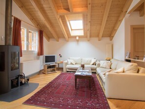 Um quarto com pé direito alto, lareira, televisão, sofá e tapete estampado.