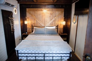 Ein Bett mit einem gemusterten Bettüberwurf, zwei Nachttischlampen und einem hölzernen Kopfteil.
