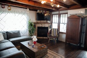 Ein Wohnzimmer mit Kamin aus Stein, einem Fernseher, einer Couch und einem Holzschrank.