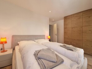 Ein Hotelzimmer mit zwei Betten, einem Holzschrank und einem Nachttisch mit Lampe.