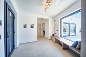 A modern interior with a large window, a bench, and a ceiling light fixture. - Villa Lucia by Istrabook – Peace, Nature & Private Pool (Marcana)