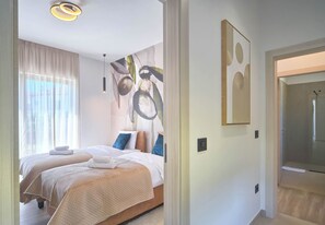 A bedroom with two beds, a large abstract painting, and a door leading to a bathroom. - Villa Lucia by Istrabook – Peace, Nature & Private Pool (Marcana)