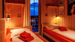 A wooden room with two beds, a window, and a poster on the wall. - Chalet Wilhelmina Appartement/Fewo, Dusche und Bad, WC, 8-Bettwohnung by Interhome (Arosa)