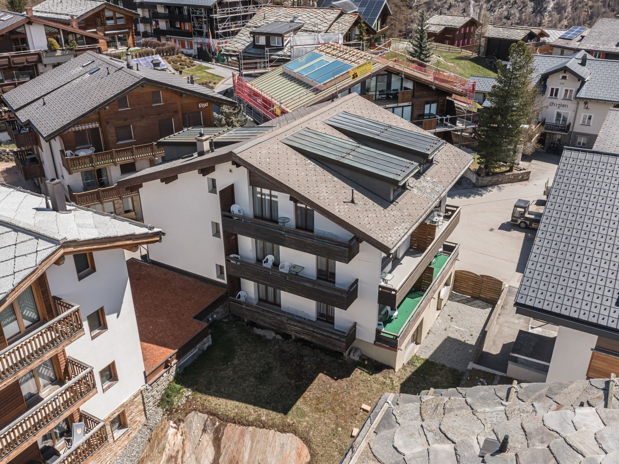 A multi-story building with balconies, a green roof, and a stone facade.