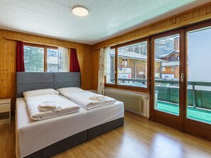 A hotel room with a large bed, wooden walls, a view of a mountain, and a balcony. - Haus Slalom Appartement/Fewo Apt #5 by Interhome (Saas-Fee)