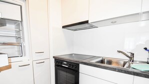 A modern kitchen with white cabinetry, a dishwasher, an oven, and a stainless steel sink. - Haus Camillo Appartement/Fewo 4-Bettwohnung Nr. 16 by Interhome (Saas-Fee)