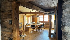 Ein rustikales Holzinnere mit Essbereich, Kamin und Steinwand.