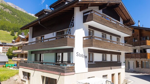 A multi-story hotel with balconies, a visible name 'Slalom,' and a parked delivery truck. - Haus Slalom Appartement/Fewo Apt #7 by Interhome (Saas-Fee)