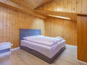 Ein Schlafzimmer mit Holzboden, einem Bett mit weißer Bettwäsche und einem weißen Nachttisch.