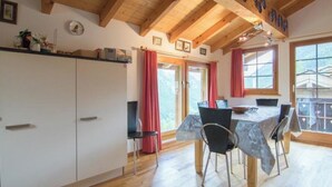 A room with wooden beams, a dining table with chairs, a kitchen area with cabinets, and large windows. - Mountain Village 11 Appartement/Fewo 6-Bettwohnung by Interhome (Saas-Fee)