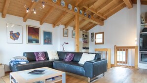 A modern living room with a sectional sofa, a coffee table, wooden flooring, and a kitchen area with a stove. - Mountain Village 11 Appartement/Fewo 6-Bettwohnung by Interhome (Saas-Fee)