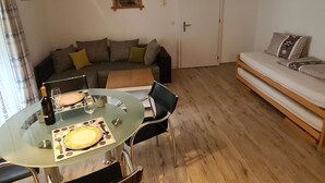 Sala de estar com mesa de jantar de vidro, um sofá e uma porta.
