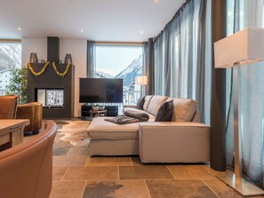 Ein modernes Wohnzimmer mit einer Couch, einem Flachbildfernseher und einem Kamin.