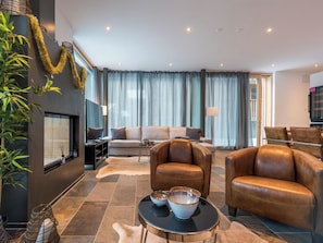 Ein modernes Wohnzimmer mit einer Couch, Ledersesseln, einem Couchtisch und einem Kamin.