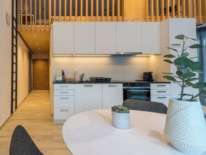 A modern kitchen with white cabinets, a round dining table, and a potted plant. - Montela Pavillon - Holiday Stay Appartement/Fewo by Interhome (Saas-Grund)
