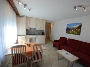A compact living space with a dining area, kitchenette, and a red sofa. - Mischi Appartement/Fewo 4-Bettwohnung Nr. 12 by Interhome (Saas-Fee)