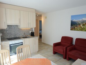 A compact living space with a kitchen, dining area, and a red armchair. - Mischi Appartement/Fewo 4-Bettwohnung Nr. 12 by Interhome (Saas-Fee)