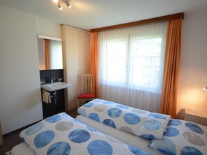 A hotel room with two beds, a small bathroom with a sink, and a window with curtains. - Mischi Appartement/Fewo 4-Bettwohnung Nr. 12 by Interhome (Saas-Fee)