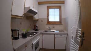 A compact kitchen with white cabinets, a stove, a sink, and a window above the sink. - Swiss Chalet Appartement/Fewo 2-Bettwohnung Nr. 5 by Interhome (Saas-Fee)