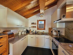 A modern kitchen with white cabinets, a wooden ceiling, a window, and a built-in microwave. - Chalet Flair Appartement/Fewo 4-Bettwohnung by Interhome (Saas-Fee)