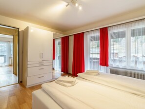 A hotel room with a bed, a wardrobe, and a window with curtains. - Haus City Appartement/Fewo Apt #4 by Interhome (Saas-Grund)