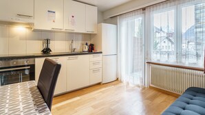 Eine moderne Küche mit weißen Schränken, einem Herd und einem Essbereich mit Tisch und Stühlen.