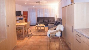 Un espacio habitable compacto con un sofá, una pequeña mesa de comedor, una silla y un armario.