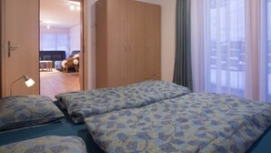 Habitación de hotel con cama, armario, escritorio y vistas al exterior.
