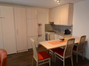 A compact kitchen with a dining area, featuring a granite countertop, a kettle, and a bowl of fruit on the table. - Mischi Appartement/Fewo 4-Bettwohnung Nr. 3 by Interhome (Saas-Fee)